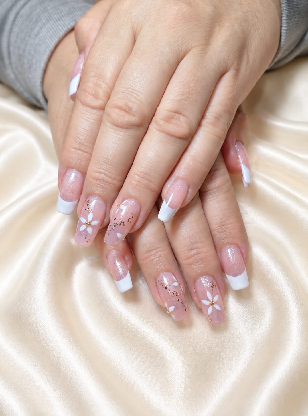 Uñas francesas largas con flores delicadas sobre tela satinada